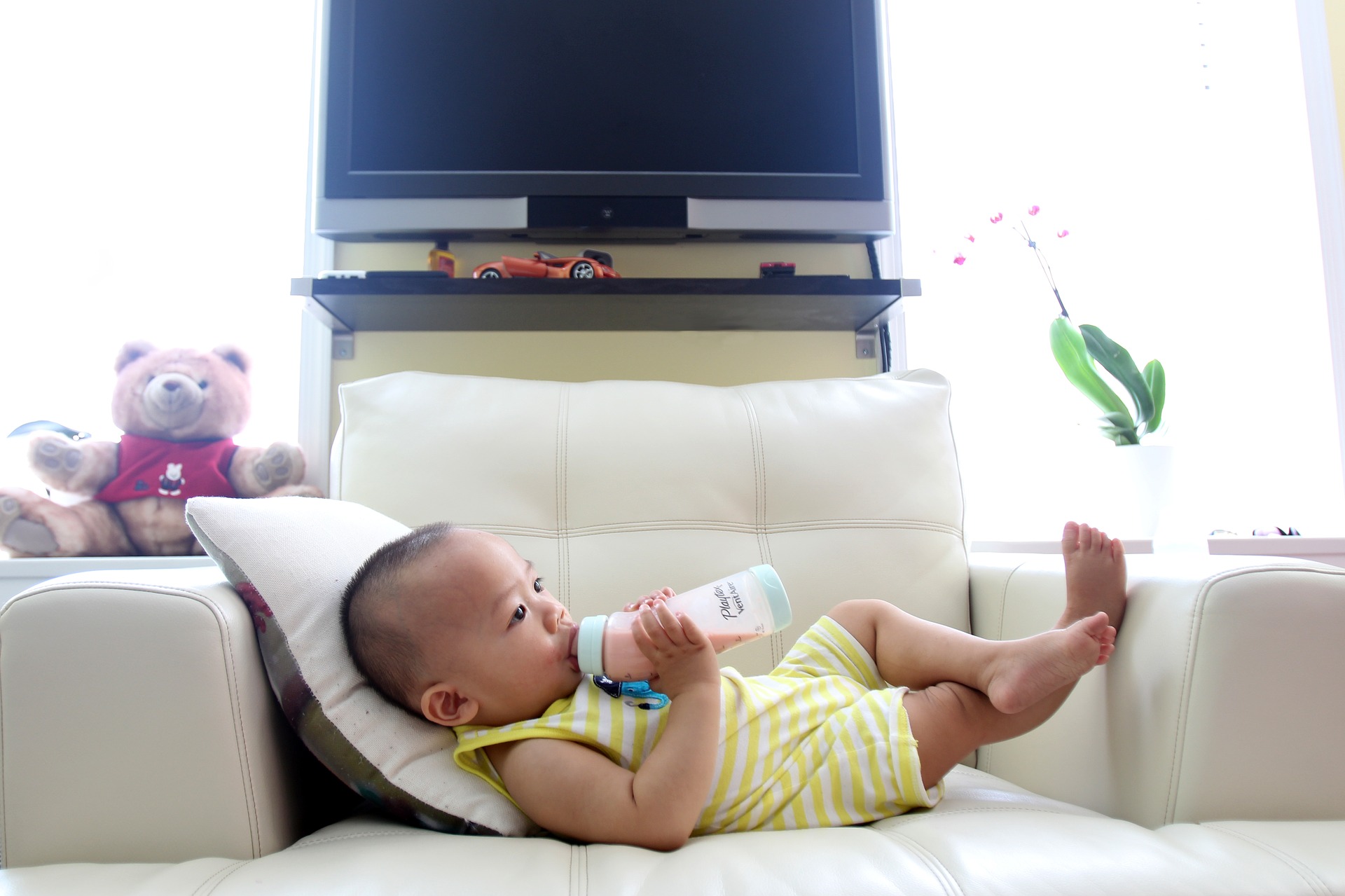 Baby drinking milk on a sofa