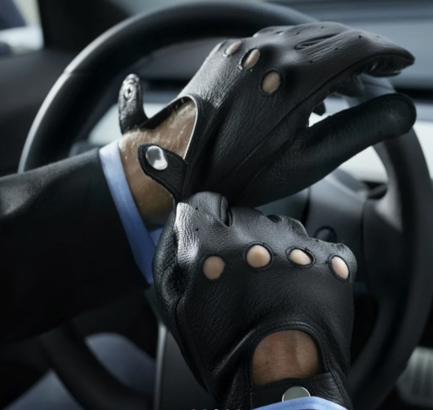 A pair of hands wearing the gloves whilst holding onto a steering wheel