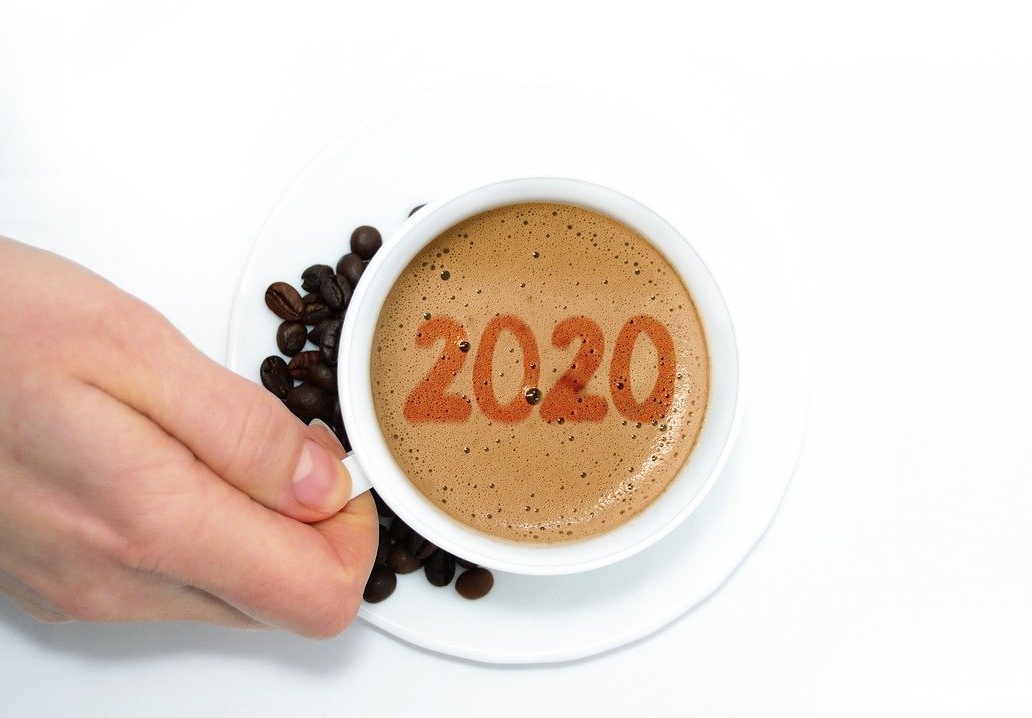 Hand holding a cup with 2020 in the coffee foam